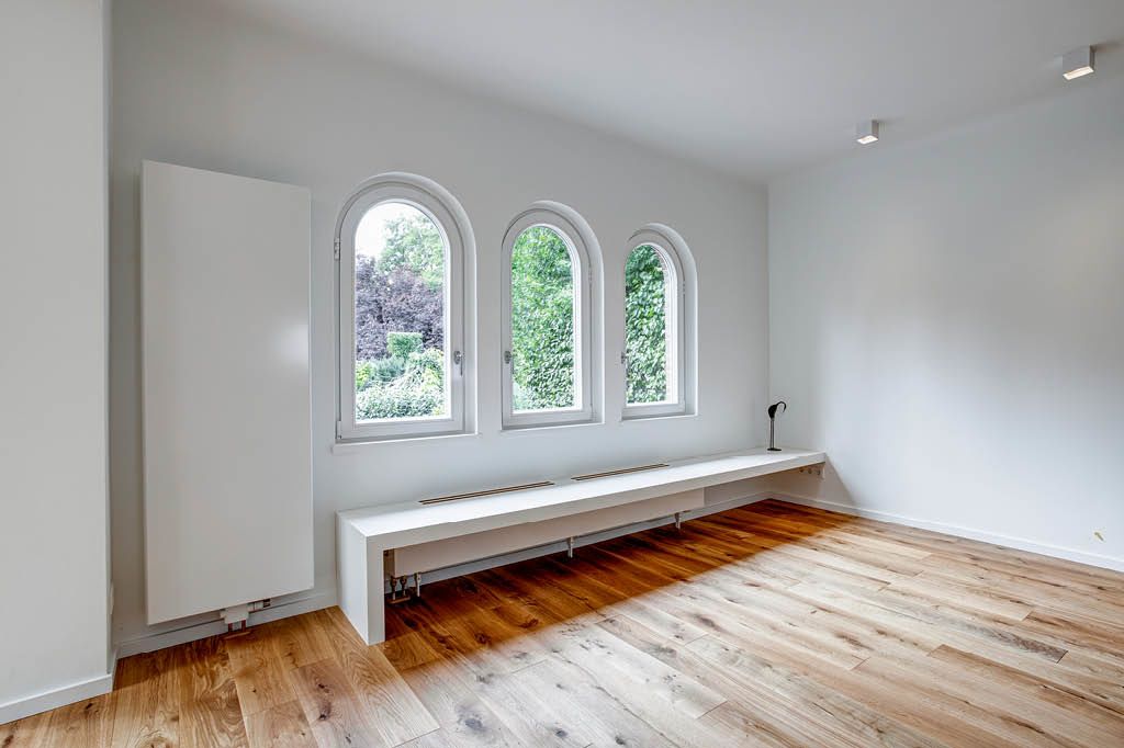 weiße Sitzbank nach Maß vom Tischler aus HPL High Pressure Laminate Multiplex Multiplexplatten mit Lüftungsschlitzen über Heizung Heizkörper